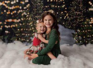 Experience Austin Baby Photography sisters sitting together on Christmas tree set