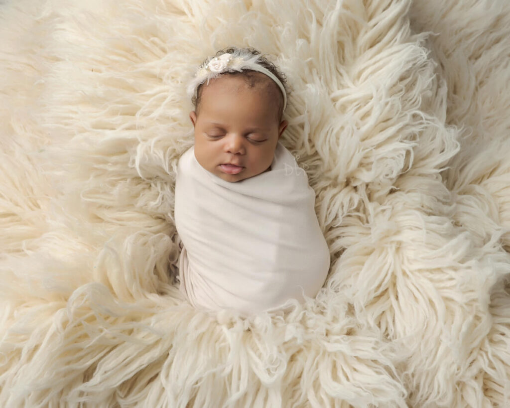 Petite wrapped session by Dazzling Light Photography features newborn baby girl wrapped in cream laying on a cream flokati rug